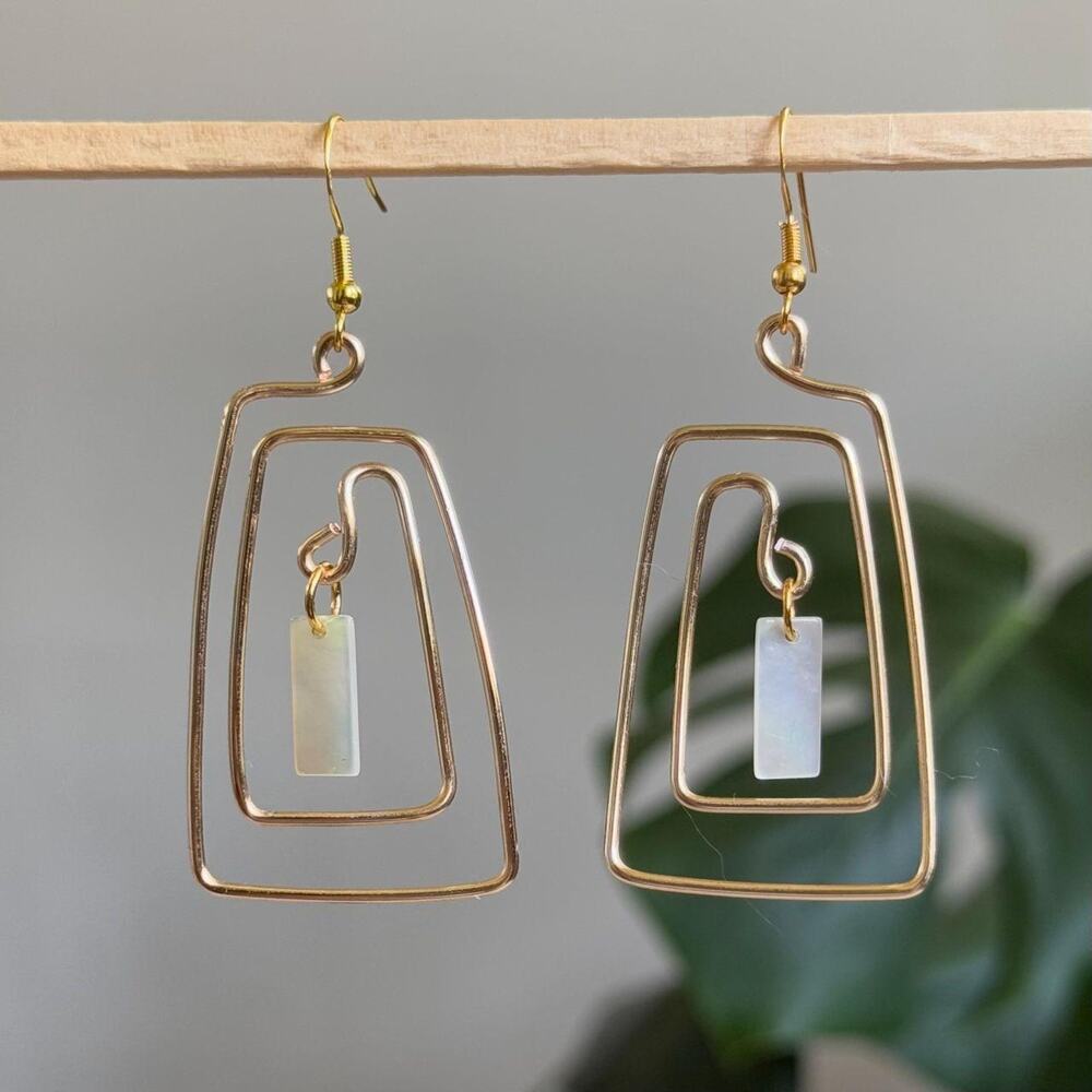 handmade gold spiral earrings with a dangling iridescent mother of pearl disc